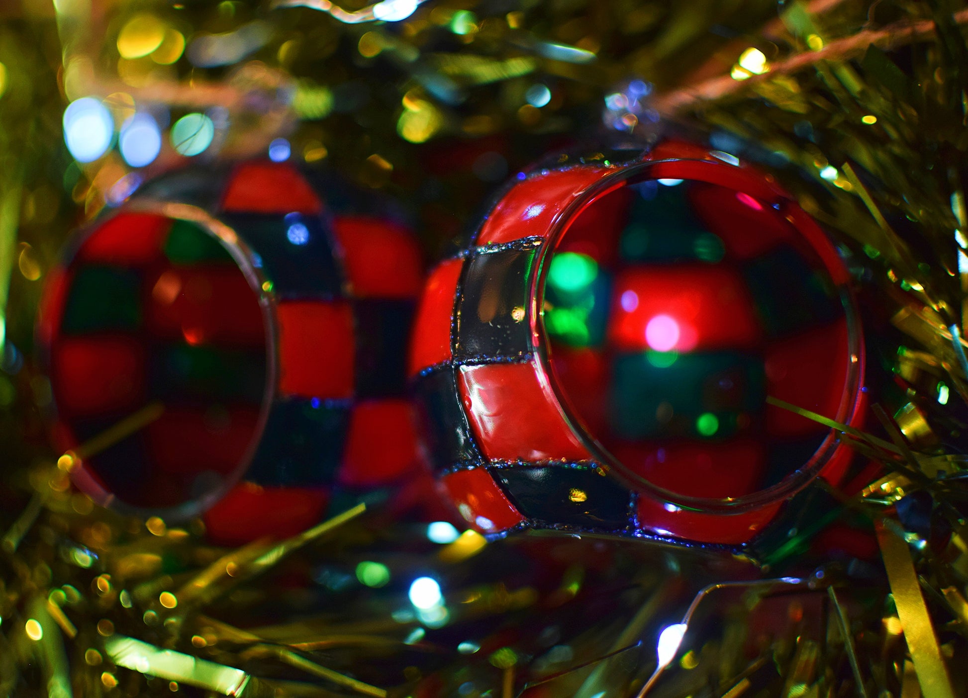 Close-up of red and green checkered Christmas ornaments on a blurred festive background